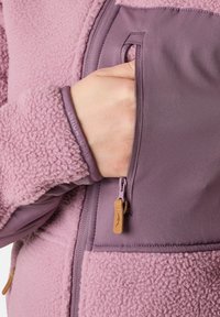 Fleecejack met een gedempte paarse kleur en een ritszak. Textuur materiaal met gladde zadelinzetten. Leren accent aan de rits.