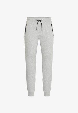 Graue Sweatpants aus weichem Stoff mit einem Kordelzugbund, schmal zulaufenden Beinen und schwarzen Reißverschluss-Taschen an den Seiten.