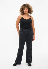 Zwarte flared jeans met een gladde textuur, voorzien van riemlussen en zakken. Gecombineerd met een zwart tanktop, met een eenvoudig ontwerp.