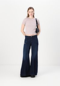 Maglietta corta di un delicato colore viola, jeans ampi blu scuro con tasche e borsa a tracolla nera. Tessuto liscio e texture denim a contrasto.