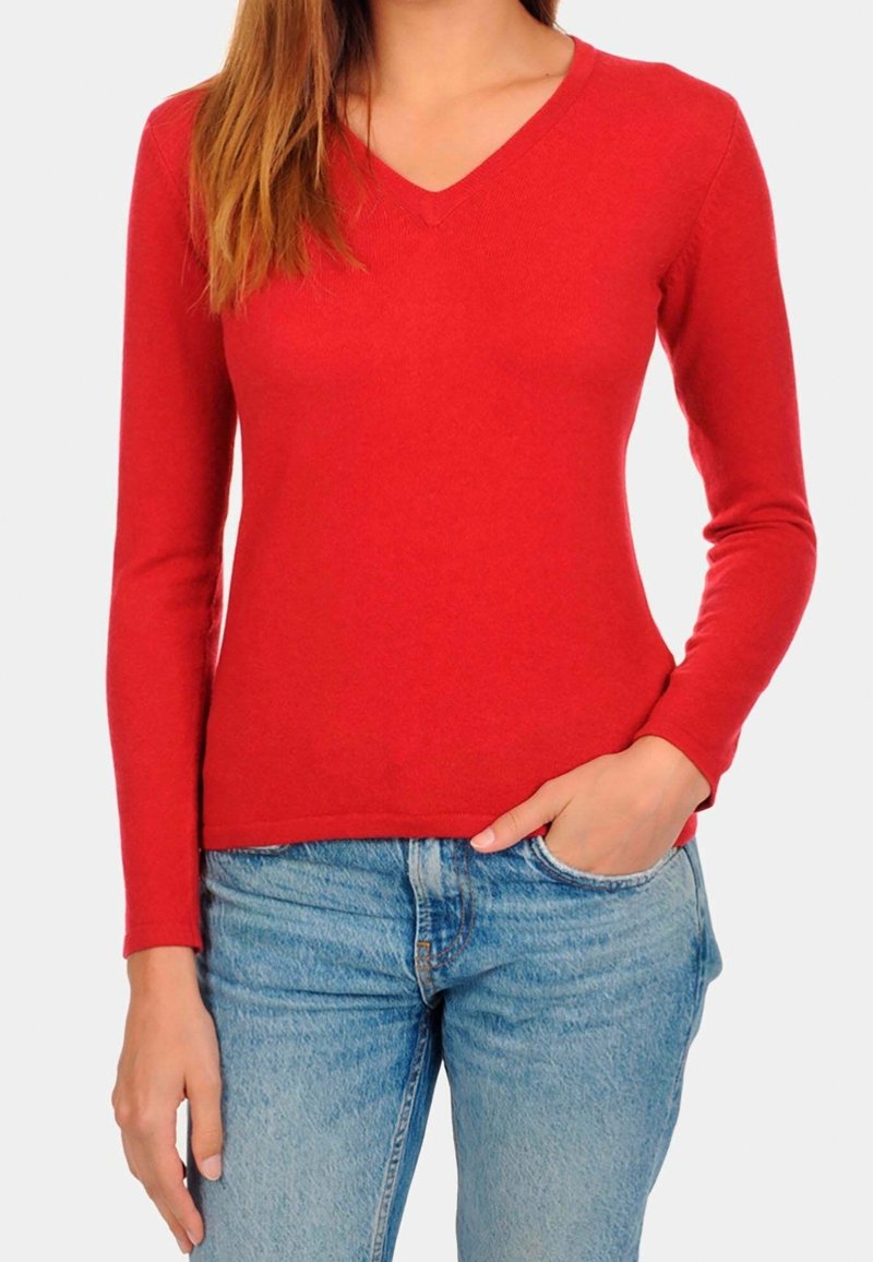 Czerwony sweter z długim rękawem w serek o dopasowanym kroju, wykonany z miękkiego materiału. Połączony z jasnoniebieskimi dżinsami, prezentując luźny wygląd.