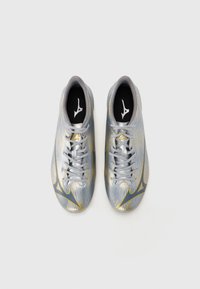 Silver athletic shoes with a textured upper, featuring gold and navy accents. Flat laces and logo on the tongue. Rounded toe design.
