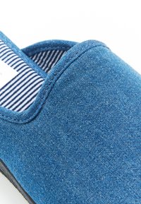 Zapato slip-on de denim azul con punta redondeada, superficie texturizada y forro interior a rayas.