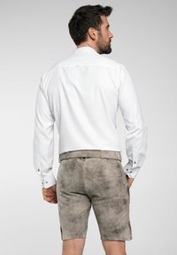 Witte langmouwen overhemd met knoopmanchetten, gecombineerd met grijze suède shorts met zijzakken en een riemlus, gezien van achteren.