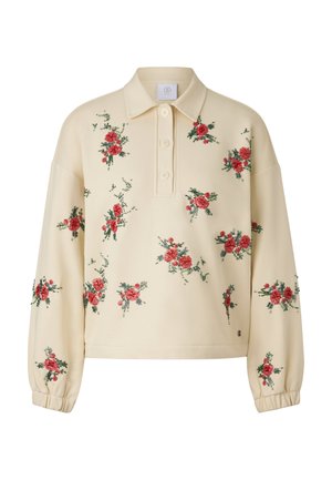 Beżowy sweter z kołnierzem, ozdobiony czerwoną, kwiatową haftowaną dekoracją na przodzie. Ma luźny krój i elastyczne ściągacze na rękawach.