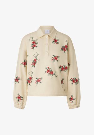 Beżowy sweter z kołnierzem, ozdobiony czerwoną, kwiatową haftowaną dekoracją na przodzie. Ma luźny krój i elastyczne ściągacze na rękawach.