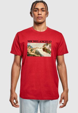 Rød bomulds t-shirt med en trykt kunstværk af Michelangelo, der viser figurer, der rækker ud. Teksten "MICHELANGELO" vises fremtrædende over billedet.