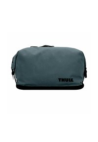 Bolso de aseo de viaje rectangular gris compacto de Thule con cremallera negra y logo sobre un fondo blanco.