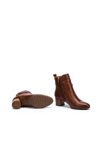 Brown leather ankle boots with a round toe, side zipper, and stacked heel; features vertical stitching and a textured sole.