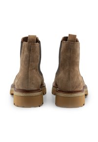 Stivaletti in suede marrone con suola in gomma spessa, pannelli laterali elastici e una linguetta sul retro per facilitare l'indossamento.