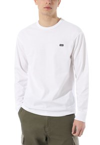 Långärmad vit T-shirt gjord av bomull. Har en liten svart Vans-logotyp på bröstet. Mjuk textur och klassisk rundhalsdesign.