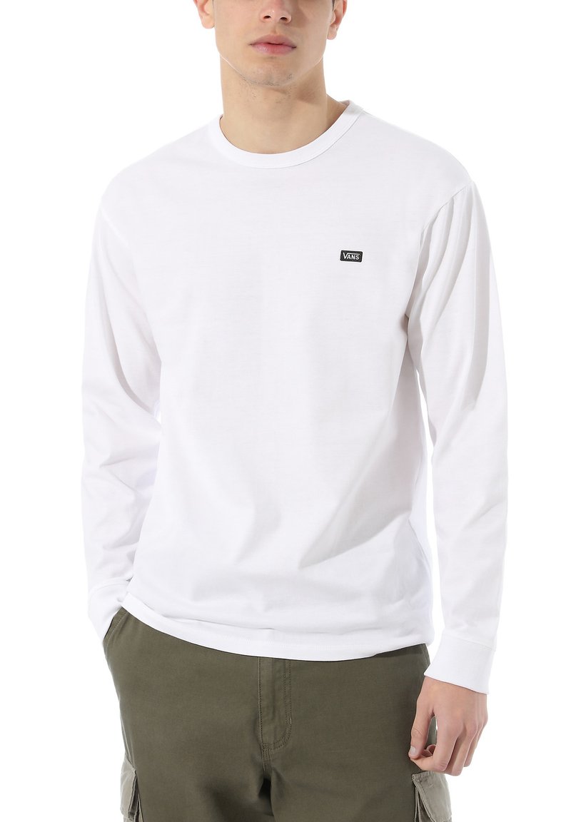 Långärmad vit T-shirt gjord av bomull. Har en liten svart Vans-logotyp på bröstet. Mjuk textur och klassisk rundhalsdesign.