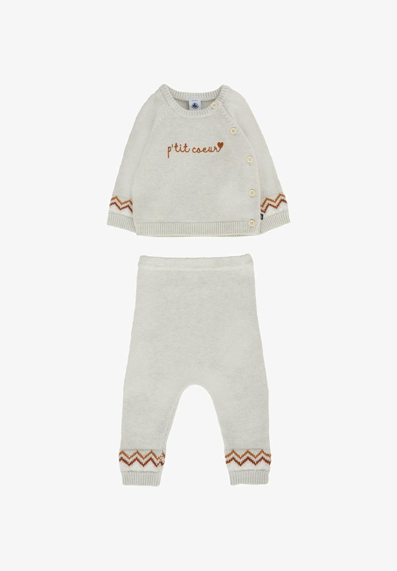 Lichtgrijs gebreid babyoutfit bestaande uit een top met knopen en de tekst "p'tit cœur", gecombineerd met bijpassende broekjes met een zigzagpatroon bij de manchetten.
