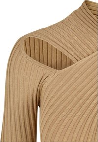 Haut long en tricot beige côtelé avec une coupe asymétrique et une découpe à l'épaule, affichant une texture douce et un design ajusté.