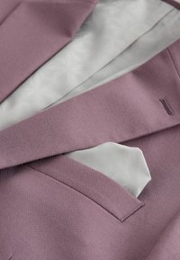 Mauve textuur blazer met een wit, patroonzakdoek en een witte, met bloemen bedrukt satijnen voering die zichtbaar is onder het revers.