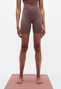 Μωβ ποδηλατικά σορτς με ψηλή μέση, κατασκευασμένα από λεία, ελαστική ύφανση. Διαθέτουν εφαρμοστή κοπή με μήκος έως το γόνατο και ελάχιστη ραφή.