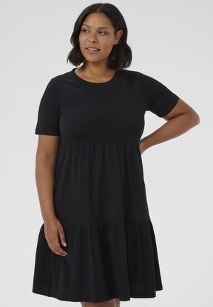 Schwarzes Baumwollkleid mit kurzen Ärmeln, runder Ausschnitt und gestuftem Rüschensaum. Glatte Textur und lockere Passform.