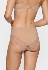 Beżowa bielizna z gładkim przodem i delikatnym koronkowym wykończeniem w liściasty wzór z tyłu, tworząca bezszwowy design.