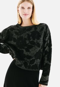 Pull court noir avec un motif floral texturé, doté d'un col rond et de manches longues, fabriqué à partir d'un matériau tricoté doux.