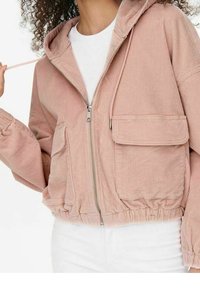 Rosa corduroy kort jacka med huva, framdragkedja och elastisk midja. Har två bröstfickor och strukturerad tyg.