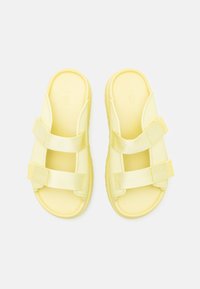Sandales glissantes jaunes avec deux sangles réglables, un coussinet texturé et une semelle épaisse pour plus de confort. Fabriquées en matériau léger.