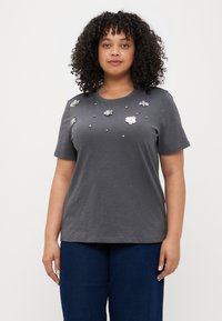 Grå T-skjorte med kort erme som har blomsterdekorasjoner og perlesmykker over fronten, laget av mykt stoff med en avslappet passform.