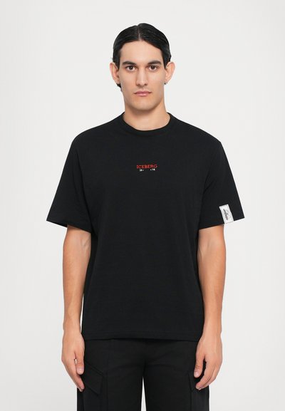 Schwarzes T-Shirt mit kurzen Ärmeln aus Baumwolle, das ein kleines rotes "ICEBERG 19 - 74" Logo auf der Brust und ein weißes Etikett am linken Ärmel aufweist.