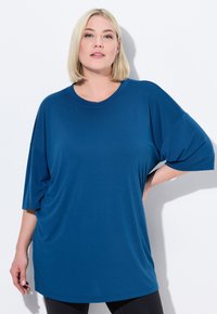 T-shirt a maniche corte, girocollo e vestibilità ampia di colore blu profondo, realizzata in tessuto morbido con una finitura liscia e una leggera caduta.