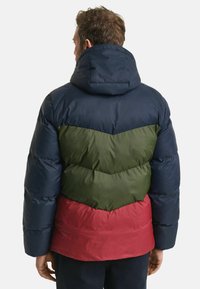 Gepolsterte Parka mit Kapuze; verfügt über ein Zickzackmuster in Marineblau, Grün und Rot; glatte Textur und gesteppten Abschnitten.
