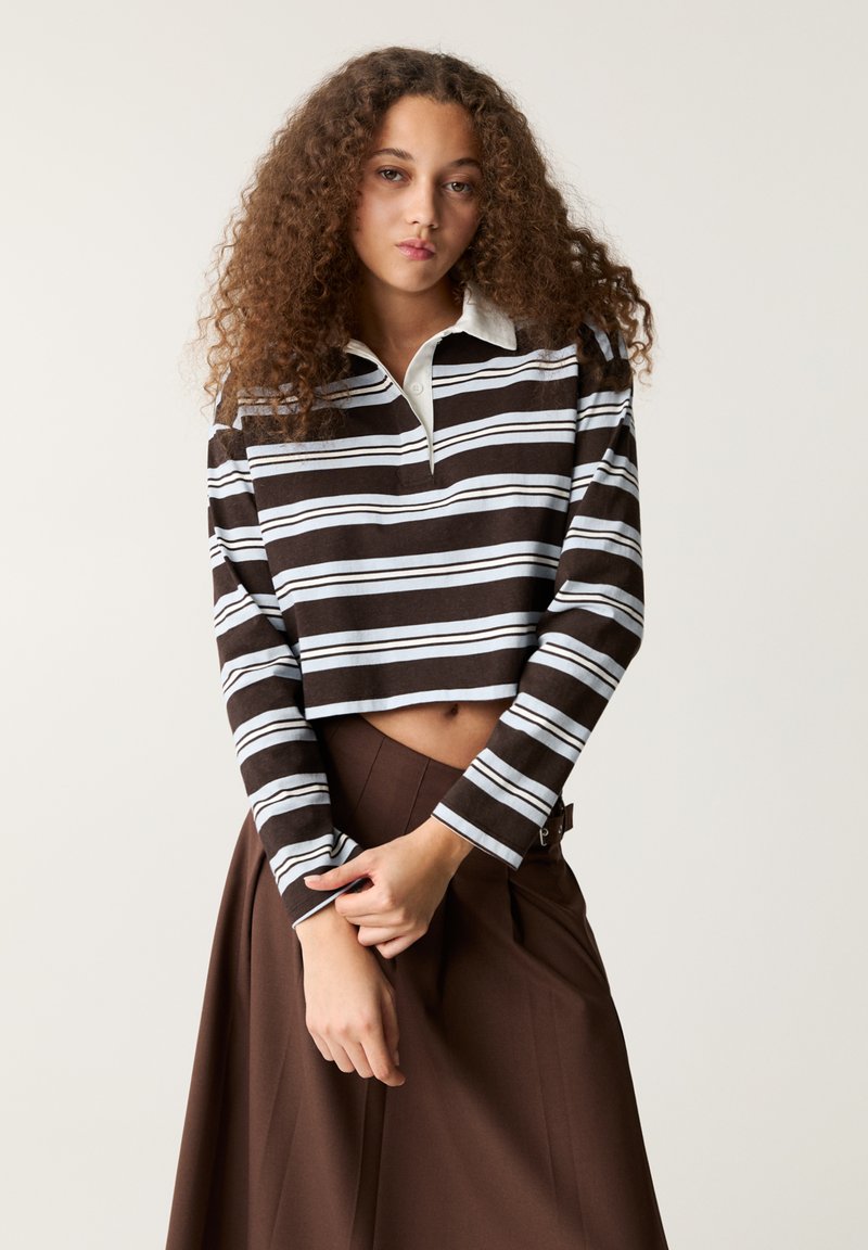 Hnedo-biely pruhovaný cropped polo s dlhým rukávom a svetlomodrým golierom, ktorý má voľný strih a mäkkú textúru.