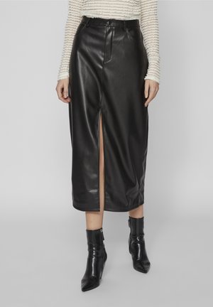 Czarna spódnica midi z ekologicznej skóry z rozcięciem z przodu, noszona z dopasowanym, teksturowanym, dopasowanym longsleevem i czarnymi botkami z ostrym noskiem.