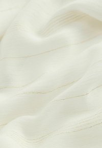 Tissu blanc avec de subtiles rayures dorées, présentant une surface douce et texturée ainsi qu'un design léger et fluide.