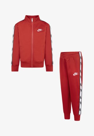 Jachetă și pantaloni atletici roșii, confecționați dintr-un material neted. Jacheta are logo-ul alb Nike și dungi laterale; pantalonii dispun de o talie elastică.
