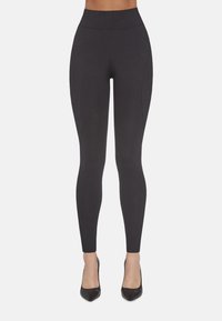 Czarne, wysoki stan legginsy wykonane z elastycznego materiału z bocznymi szwami. Połączone z czarnymi szpilkami z ostrym noskiem. Gładka tekstura, dopasowany krój.