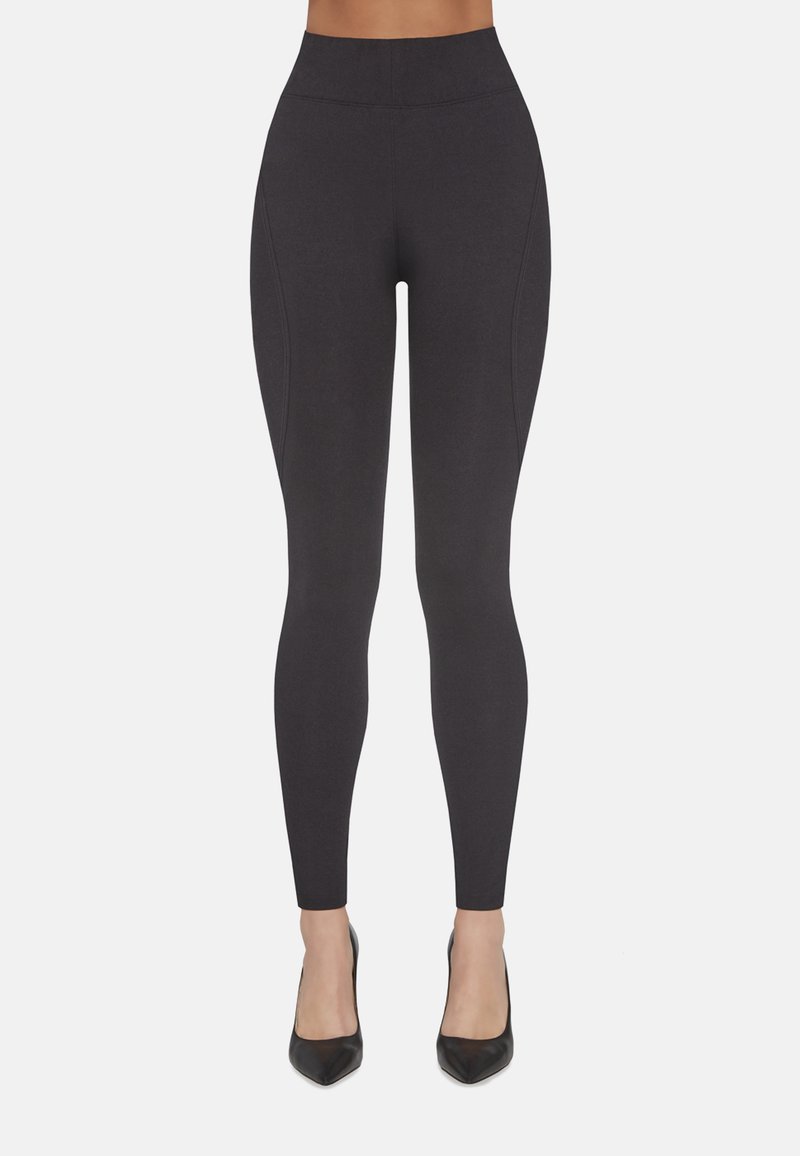 Czarne, wysoki stan legginsy wykonane z elastycznego materiału z bocznymi szwami. Połączone z czarnymi szpilkami z ostrym noskiem. Gładka tekstura, dopasowany krój.