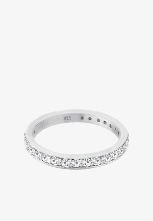 Bague en argent avec une rangée de petits cristaux transparents incrustés autour de la surface extérieure, marquée "925" à l'intérieur de la bague.