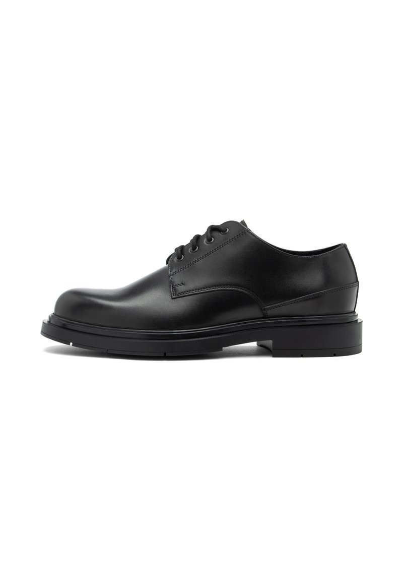 Chaussures en cuir noir avec un bout arrondi, un design à lacets et une semelle en caoutchouc plate. Elles présentent une texture lisse et des détails de couture minimes.