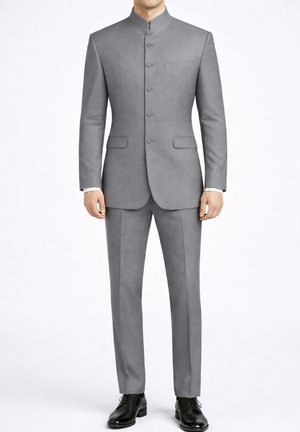 Homme portant un costume gris clair cintré avec un col mandarin, devant boutonné, pantalon assorti et chaussures habillées noires sur fond blanc.