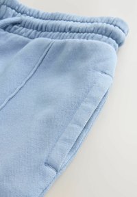 Pantalon de jogging bleu clair avec une finition texturée, doté d'une taille élastique et de poches latérales pour plus de praticité.