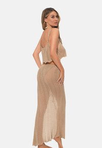  kompletny zestaw składający się z dwóch części z dzianiny, w odcieniu beżowym, składający się z krótkiego topu na regulowanych ramiączkach i długiej spódnicy z bocznym rozcięciem. Całość zdobiona teksturalnym wzorem.