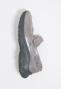 Hallikate suede kingad, millel on Velcro rihm, hõbedased sädelused ja tekstureeritud must kummitald. Omab ümarat nina ja hingavat disaini.