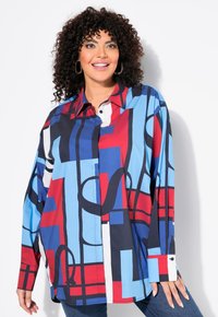 Camma oversize colorata in cotone con una combinazione di motivi geometrici rossi, blu e bianchi; include un colletto a punta e polsini con bottoni.