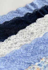 Spetskant i nyanser av blått, marinblått och vitt; har intrikata blommönster och scallopade kanter, mjuk textur och lagerarrangemang.