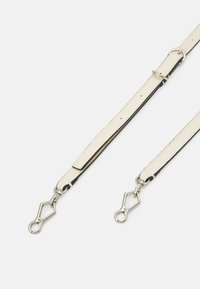 Skórzany pasek w kolorze kremowym z czarną krawędzią, z metalowymi srebrnymi elementami i dwoma końcówkami do zaczepienia.