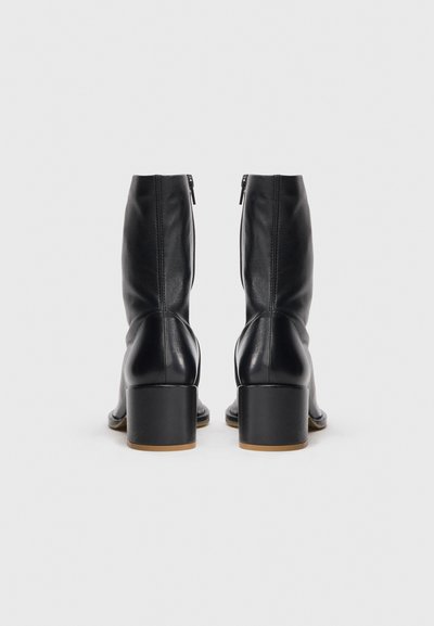 Schwarze Leder-Stiefeletten mit Reißverschluss, moderatem Blockabsatz, glatter Oberfläche und runder Zehenform. Verfügt über minimale Nähte.