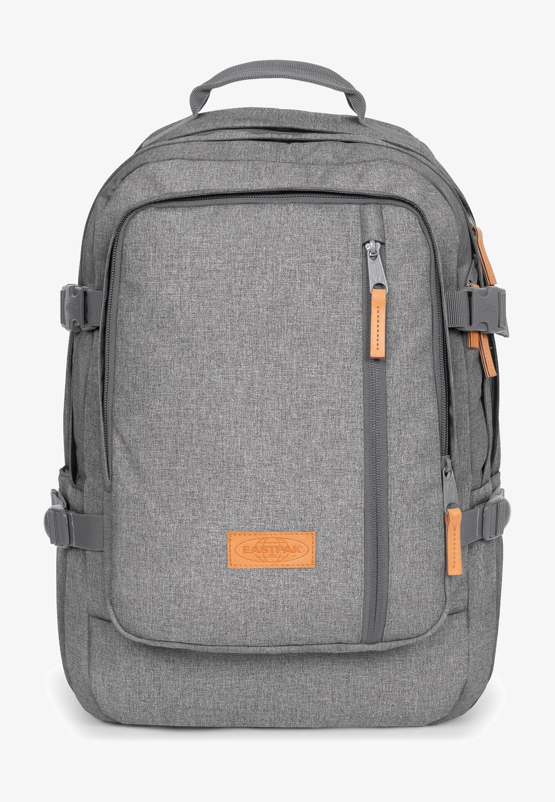 Harmaa kangasreppu suorakulmaisen muotoilun kanssa, jossa on vetoketjuja, nahkaosia, säädettävät hihnat ja teksturoitu pinta.