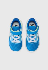 Baskets de sport bleues avec tige en maille, lacets blancs et sangle Velcro. Présente des rayures blanches et un accent vert contrastant au talon.