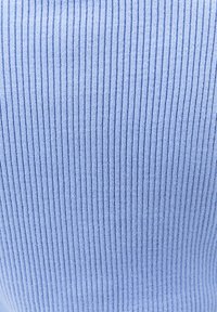 Tessuto a maglia a coste azzurro chiaro con linee verticali in rilievo, che mostra un dettaglio ravvicinato del motivo e della texture del materiale.