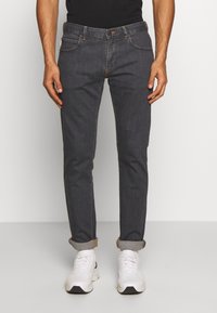 Slim-fit dark denim jeans with rolled cuffs, contrasting stitching, five-pocket design, and a classic button and zipper closure.