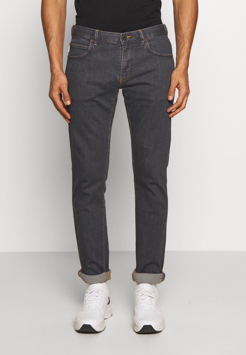 Slim-fit dark denim jeans with rolled cuffs, contrasting stitching, five-pocket design, and a classic button and zipper closure.